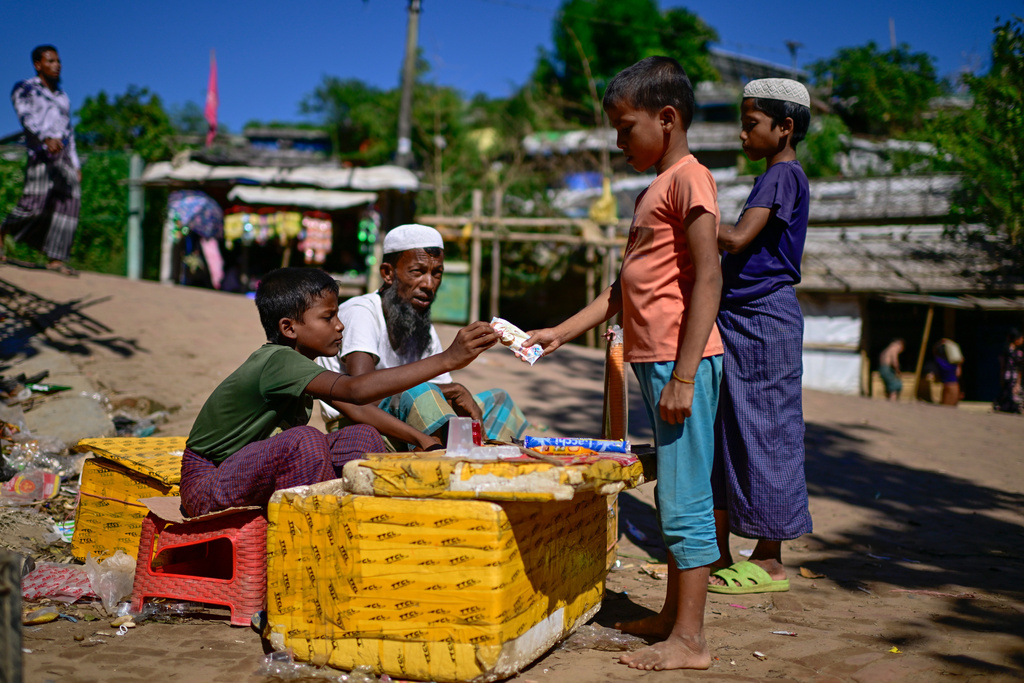 Ten-year-old Rohingya refugee Mohammed Arfan, left, sells snacks inside the Rohingya refugee camp in Cox's Bazar, Bangladesh, Friday, Nov. 21, 2025. (AP Photo/Mahmud Hossain Opu)
