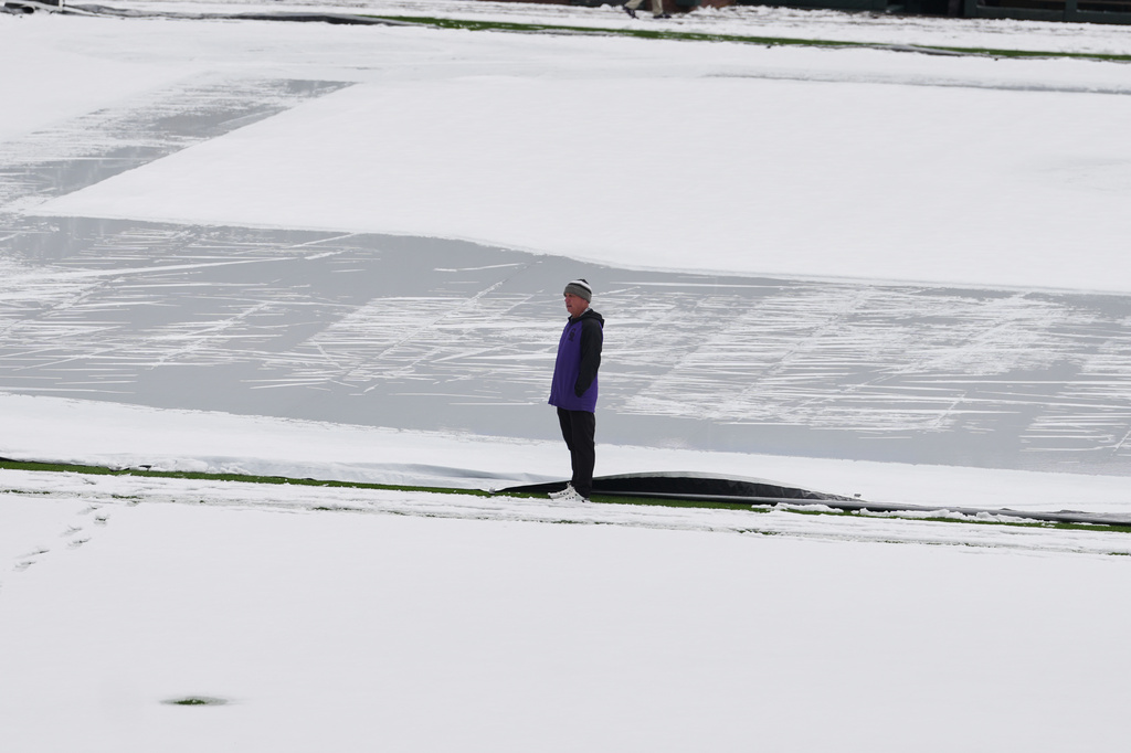 Mark Razum, head groundskeeper at Coors Field, surveys the covering of snow on the field after a spring storm blanketed the intermountain West before the Colorado Rockies host the Los Angeles Dodgers in a baseball game Friday, April 17, 2026, in Denver. (AP Photo/David Zalubowski)