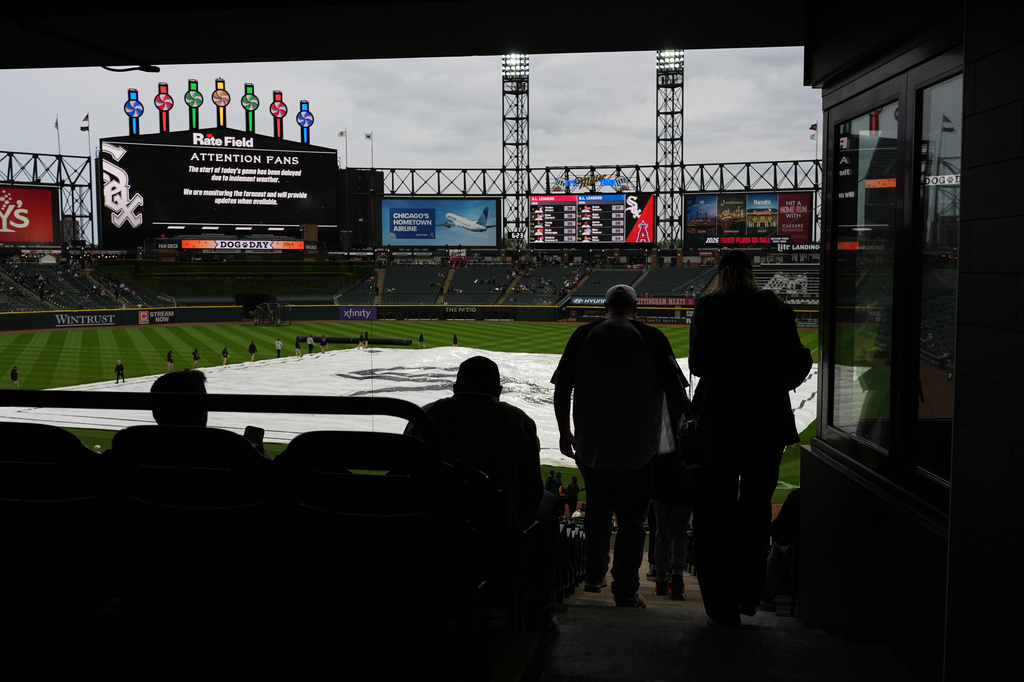 A tarp covers the infield as fans wait during a rain delay before a baseball game between the Los Angeles Angels and the Chicago White Sox in Chicago, Monday, April 27, 2026. (AP Photo/Nam Y. Huh)