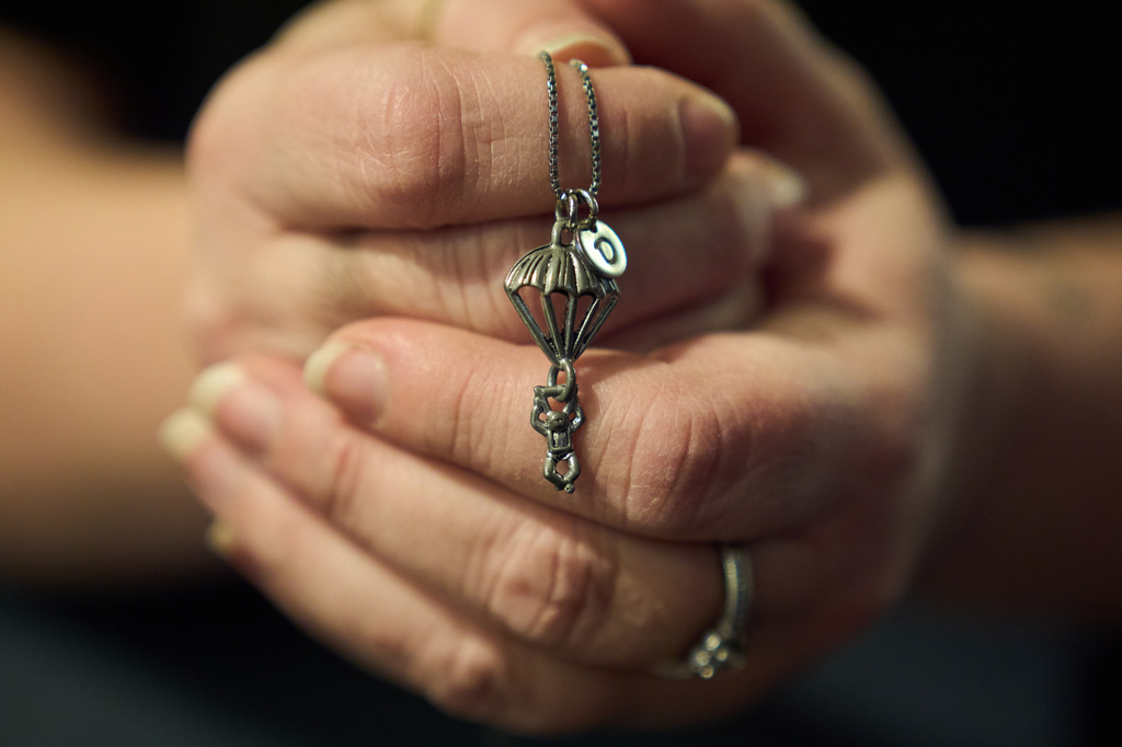 Jean Booth, who was targeted in a romance scam, holds the charm necklace she bought for her scammer, who pretended to be a paratrooper, as she poses for a portrait in Westlake, Ohio, Dec. 9, 2025. (AP Photo/David Goldman)