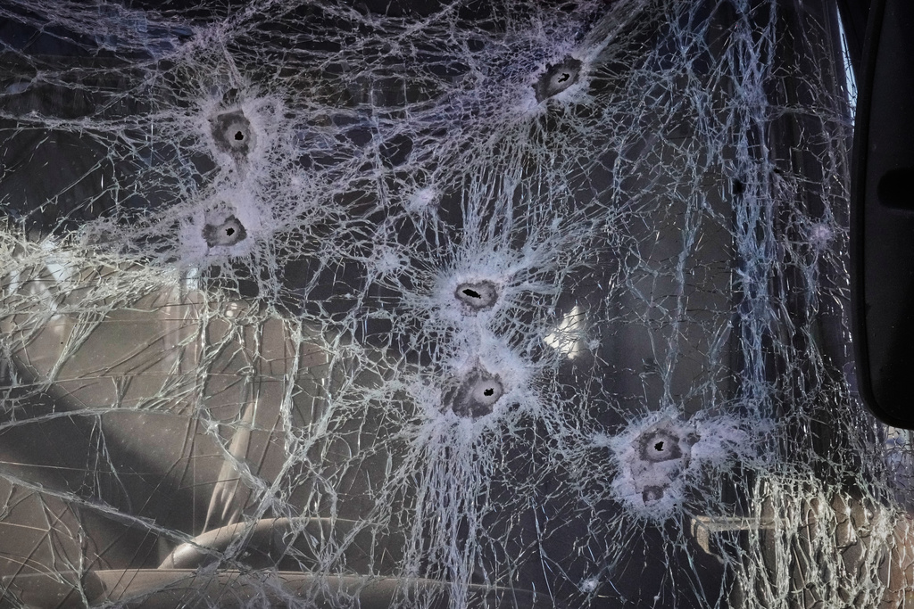 Shrapnel holes cover the glass of a damaged bus near railway workshops, following a Russia missile and drone attack, in Brovary close to Kyiv, Ukraine, Saturday, March 14, 2026. (AP Photo/Efrem Lukatsky)