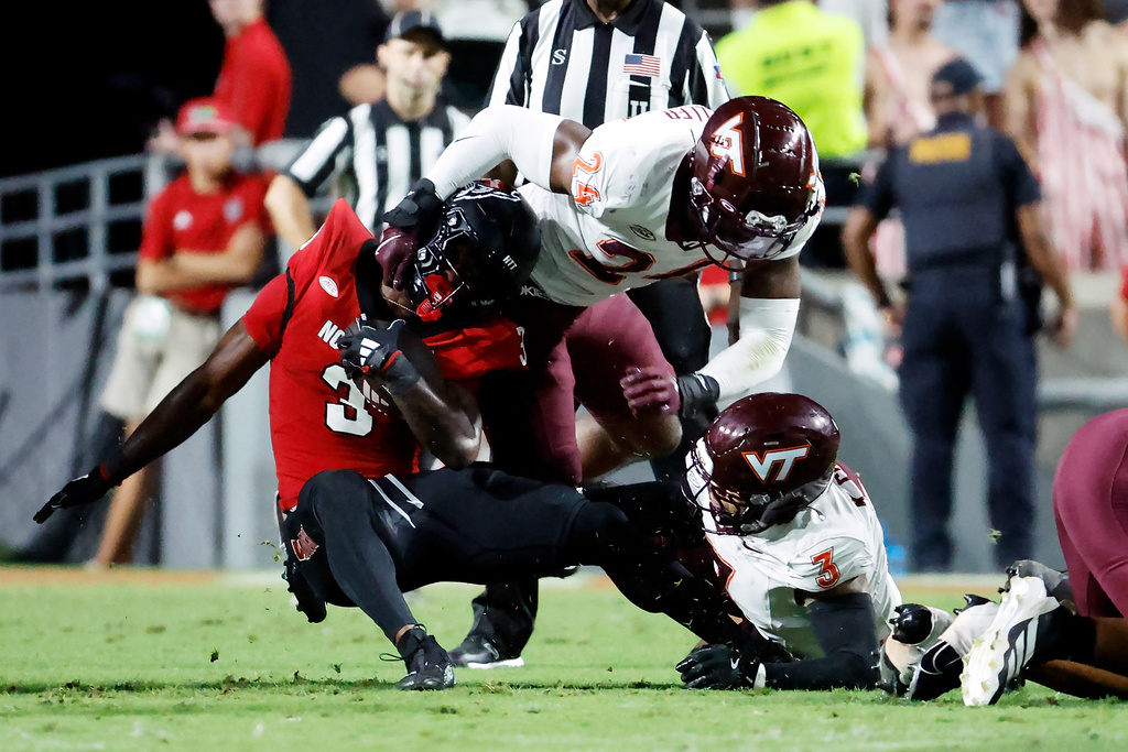 North Carolina State running back Hollywood Smothers (3) struggles in the grasp of Virginia Tech's Jaden Keller (24) with Kaleb Spencer (3) nearby during the first half of an NCAA college football game in Raleigh, N.C., Saturday, Sept. 27, 2025. (AP Photo/Karl DeBlaker)
