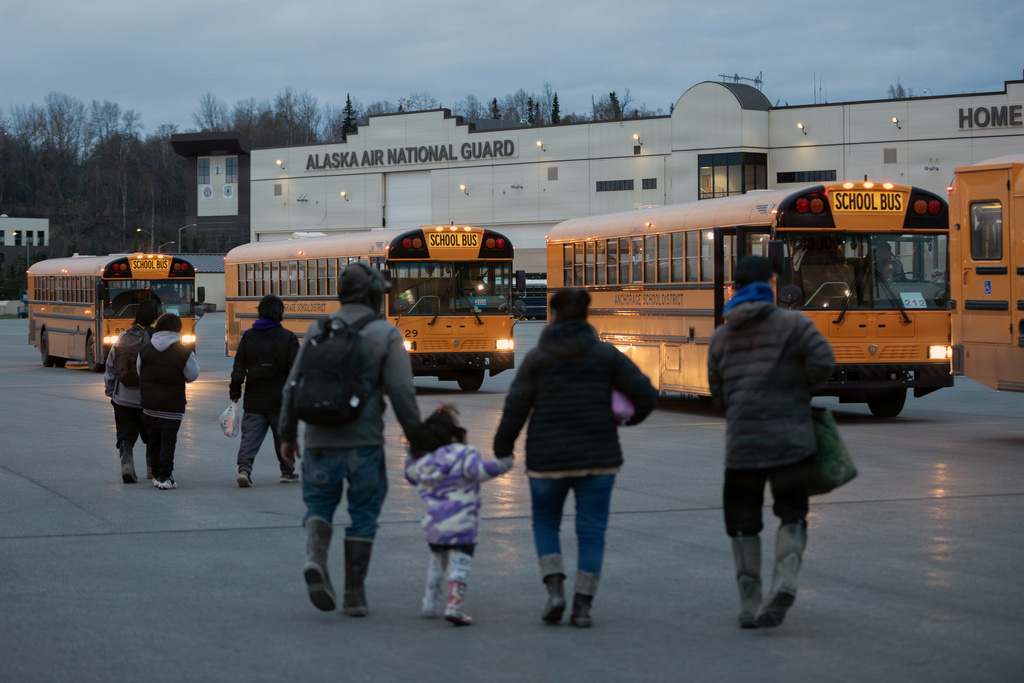 In this photo provided by the Alaska National Guard, Alaskans from West Coast communities board buses after arriving at Joint Base Elmendorf-Richardson, Alaska, Wednesday, Oct. 15, 2025. (Alejandro Pena/Alaska National Guard via AP)