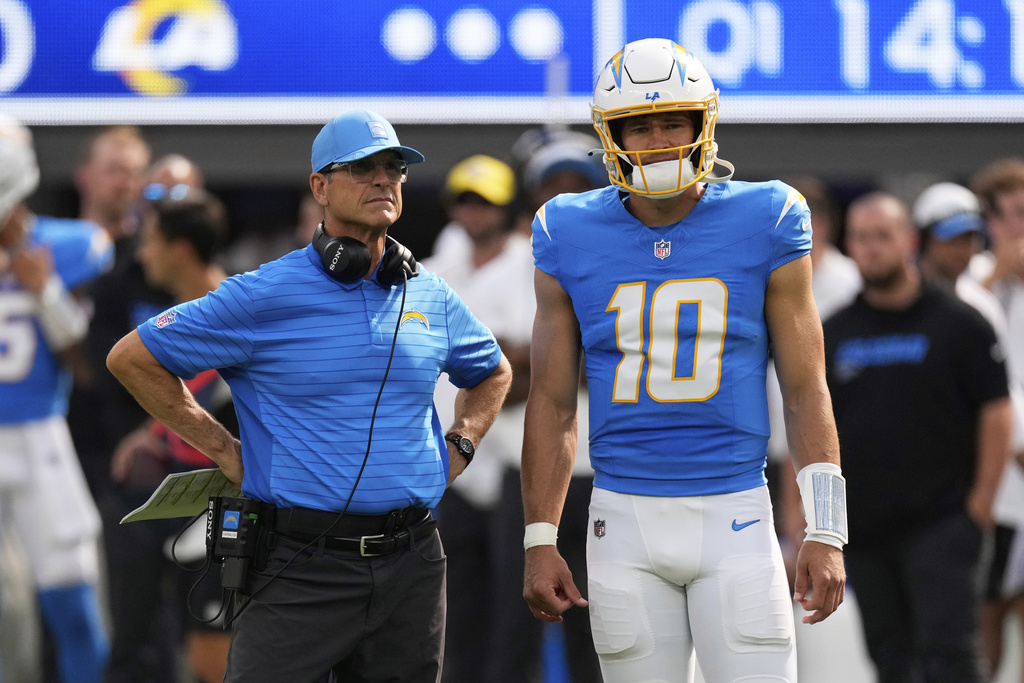 Los Angeles Chargers head coach Jim Harbaugh, left, and quarterback Justin Herbert (10) watch as wide receiver Quentin Johnston is tended to during the first half of an NFL preseason football game against the Los Angeles Rams, Saturday, Aug. 16, 2025, in Inglewood, Calif. (AP Photo/Mark J. Terrill)