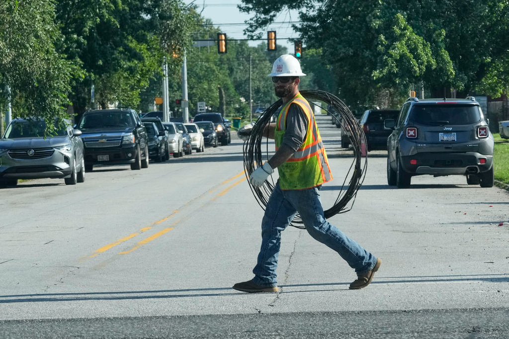 An electrical worker carries wire on the street to repair power in Gary, Ind, Thursday, Aug. 20, 2026, more than a week after a deadly storm passes through the area. (AP Photo/Nam Y. Huh)