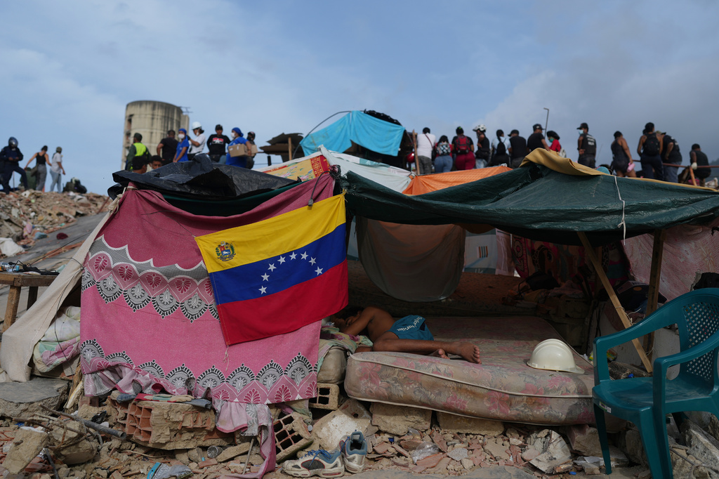 A young man sleeps as rescue workers continue searching through the rubble after the earthquakes in La Guaira, Venezuela, Saturday, July 4, 2026. (AP Photo/Ariana Cubillos)