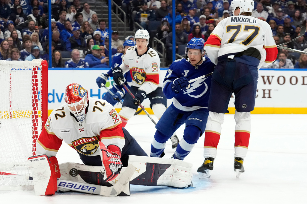 Florida Panthers goaltender Sergei Bobrovsky (72) makes a save as defenseman Niko Mikkola (77) keeps Tampa Bay Lightning center Yanni Gourde (37) from a rebound during the second period of an NHL hockey game Monday, Dec. 15, 2025, in Tampa, Fla. (AP Photo/Chris O'Meara)