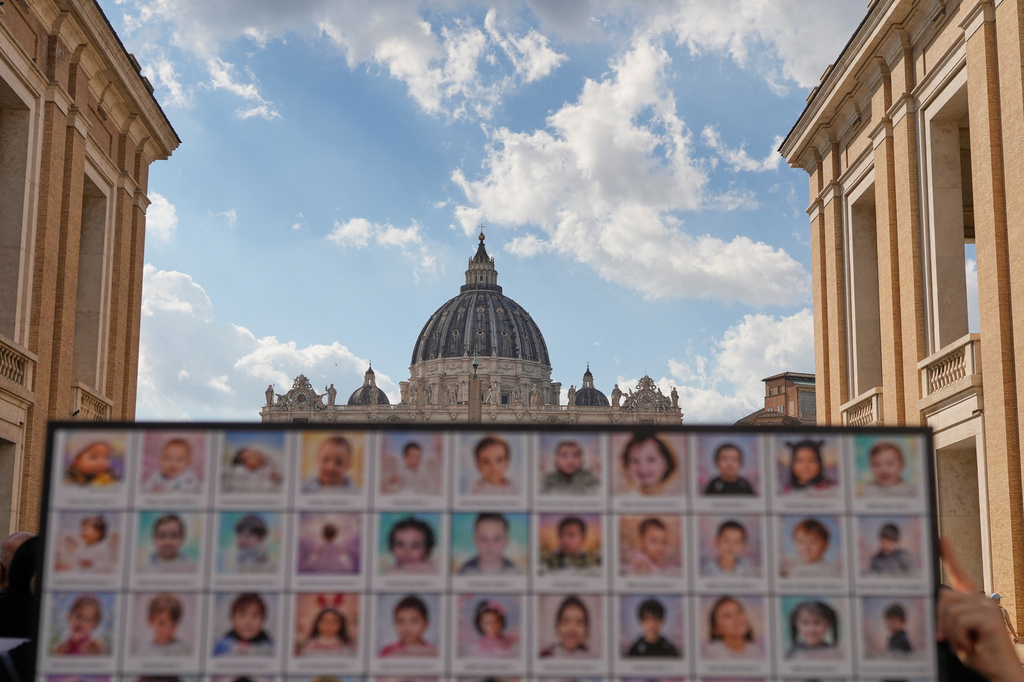 Demonstrators show a placard as they gather with priests from various countries, members of the "Priests Against Genocide" network, who carry a shroud bearing the names of 300 Palestinian and Lebanese children whom organizers say were killed by the Israeli military after ceasefires were declared, during a demonstration near St. Peter's Square at the Vatican, Tuesday, Sept. 22, 2026. (AP Photo/Gregorio Borgia)