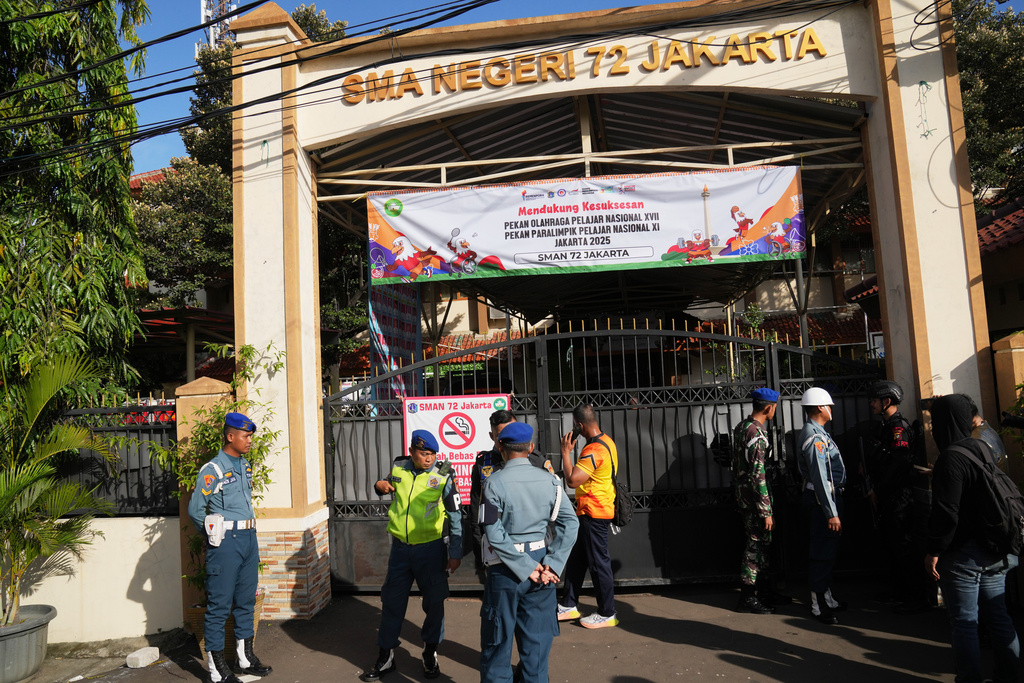 Police officers and military personnel stand guard at the gate of a school where explosions reportedly occurred, in Jakarta, Indonesia, Friday, Nov. 7, 2025. (AP Photo/Dita Alangkara)