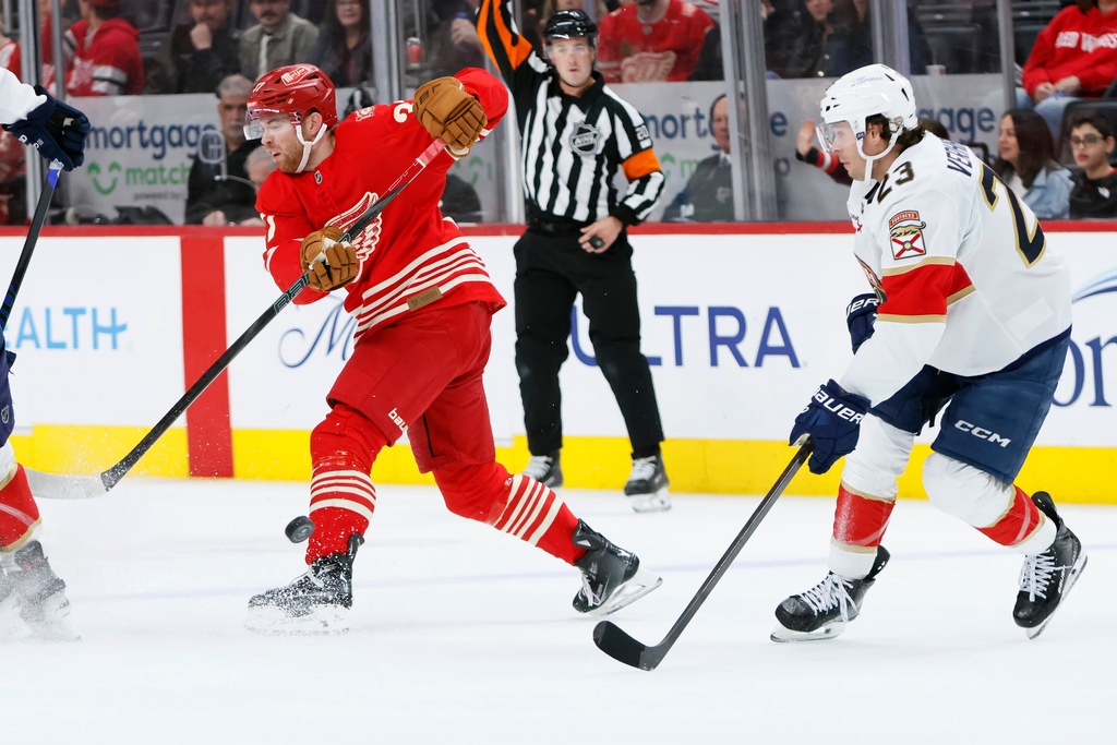 Detroit Red Wings left wing J.T. Compher, left, is pressured by Florida Panthers center Carter Verhaeghe (23) while passing the puck during the first period of an NHL hockey game Friday, March 6, 2026, in Detroit. (AP Photo/Duane Burleson)