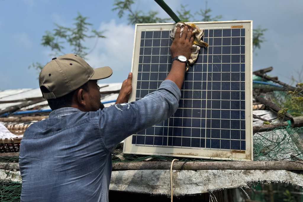 In this photo taken with a phone, Mohammed Saber cleans a solar panel to ensure it charges properly on Oct. 4, 2026, in Teknaf, Bangaldesh. (AP Photo/Abdul Khan Dkl)