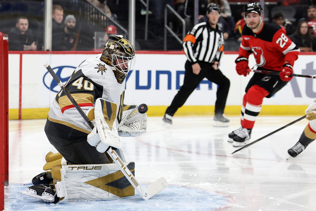 Vegas Golden Knights goaltender Akira Schmid, left, makes a save during the second period of an NHL hockey game against the New Jersey Devils, Friday, Dec. 5, 2025, in Newark, N.J. (AP Photo/Adam Hunger)