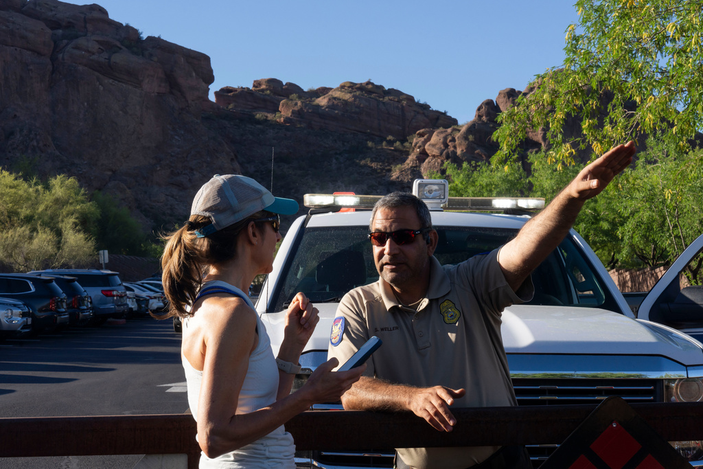City of Phoenix Park Ranger Sam Weller, right, directs a hiker away from a trailhead closed due to extreme heat at Camelback Mountain on Thursday, March 19, 2026, in Phoenix. (AP Photo/Rebecca Noble)