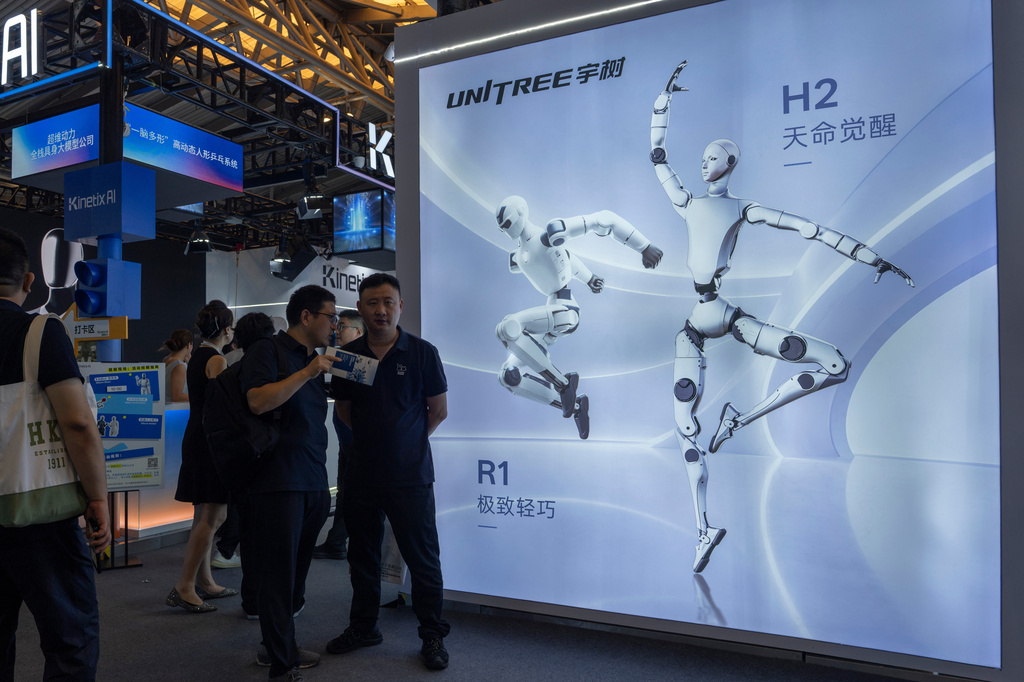 Visitors stand near advertisement for leading Chinese commercial humanoid robotics firm Unitree Robotics during the World AI Conference in Shanghai, China, on July 18, 2026. (AP Photo/Ng Han Guan)
