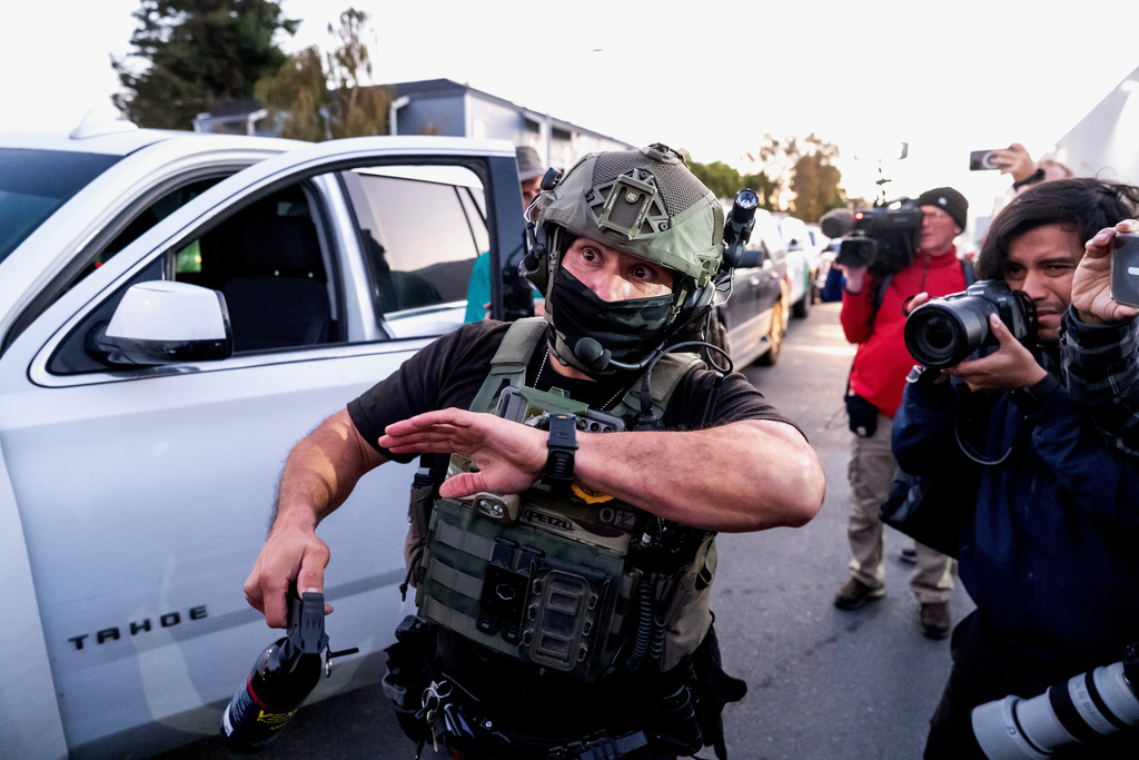 A U.S. Border Patrol officer tries to clear protesters while entering Coast Guard Base Alameda on Thursday, Oct. 23, 2025, in Oakland, Calif. (AP Photo/Noah Berger)