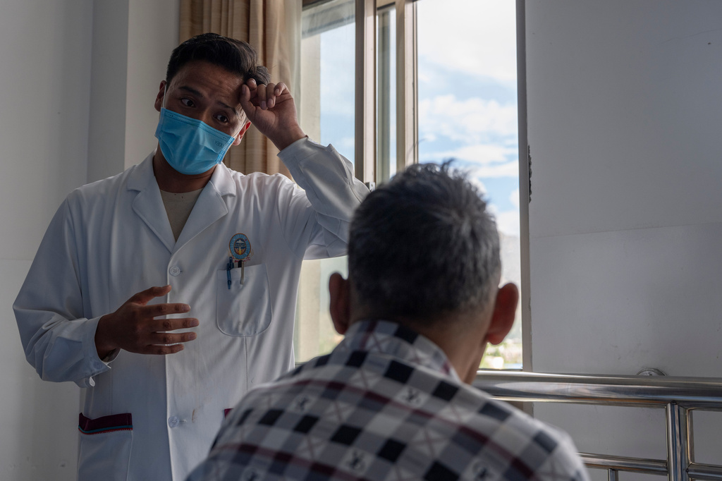 Gama, a physician, describes the therapy for a Tibetan man, right, in a ward of the Xizang Autonomous Region Hospital of Tibetan Medicine in Lhasa, in western China's Tibet Autonomous Region on Wednesday, July 22, 2026 as seen during a government organized visit for foreign journalists. (AP Photo/Ng Han Guan)