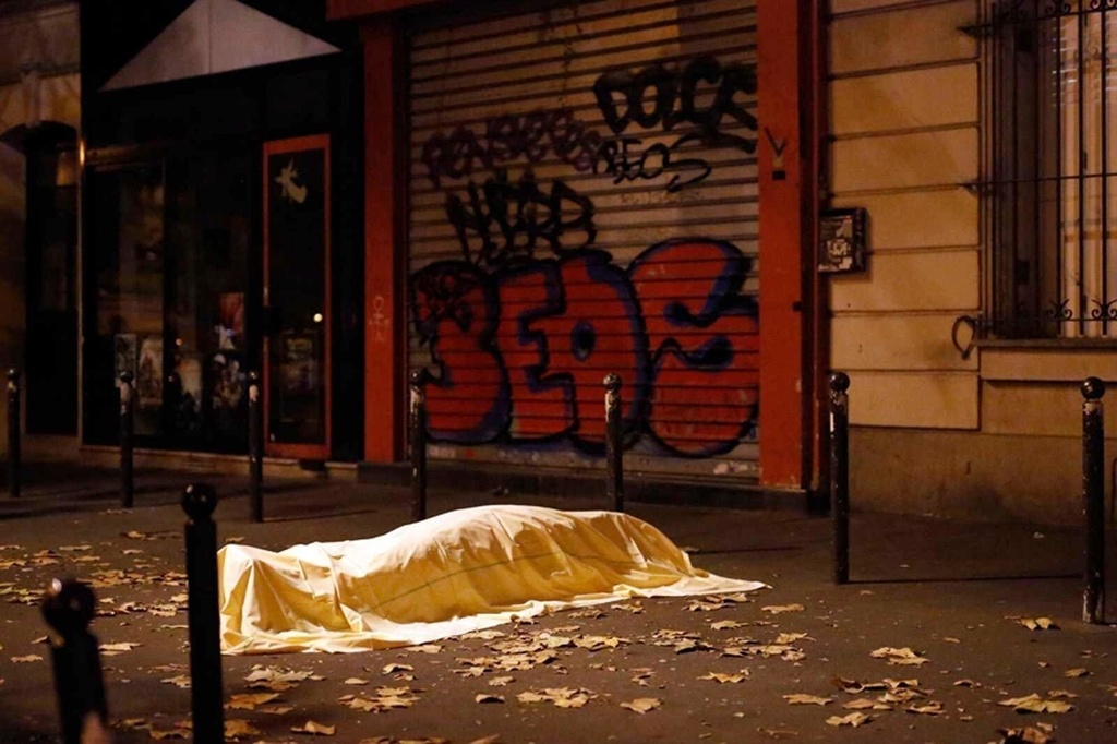FILE - A victim under a blanket lays dead outside the Bataclan theater in Paris, Nov. 13, 2015. (AP Photo/Jerome Delay, File)