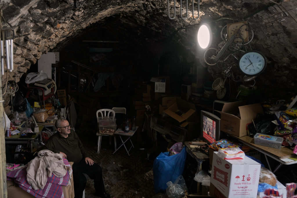 A street vendor watches the news on television after the announcement that Israel and Hamas have agreed to the first phase of a peace plan to pause the fighting, as he sits in his shop, in the Old City of Nablus, in the West Bank, Thursday, Oct. 9, 2025. (AP Photo/Majdi Mohammed)