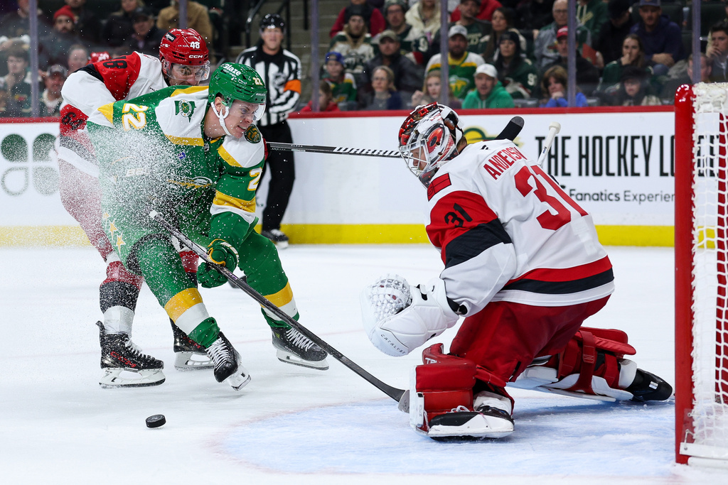 Minnesota Wild right wing Danila Yurov (22) and Carolina Hurricanes left wing Jordan Martinook (48) compete for the puck as goaltender Frederik Andersen (31) defends his net during the third period of an NHL hockey game Wednesday, Nov. 19, 2025, in St. Paul, Minn. (AP Photo/Matt Krohn)