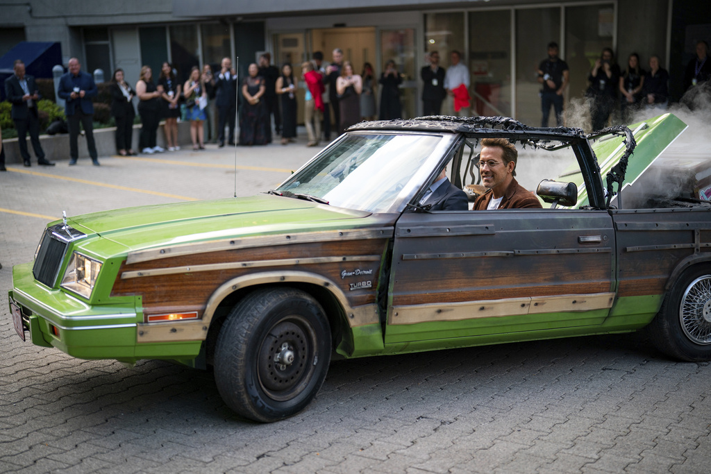 Producer Ryan Reynolds and director Colin Hanks drive in a replica prop car from the movie "Planes, Trains and Automobiles" prior to the premiere of "John Candy: I Like Me" at the Toronto International Film Festival, in Toronto on Thursday, Sept. 4, 2025. (Arlyn McAdorey/The Canadian Press via AP)