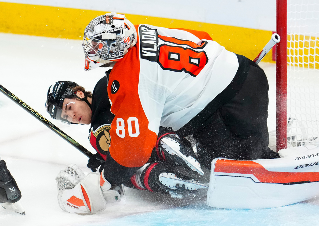 Ottawa Senators' Ridly Greig (71) slams into Philadelphia Flyers goaltender Dan Vladar (80) during third period NHL hockey action in Ottawa on Thursday, Oct. 23, 2025. (Sean Kilpatrick/The Canadian Press via AP)