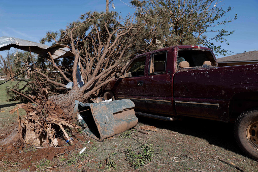 A vehicle at a home on Southgate Road sits under debris Friday, April 24, 2026, in a neighborhood that was damaged by a tornado Thursday in Enid, Okla. (AP Photo/Alonzo Adams)
