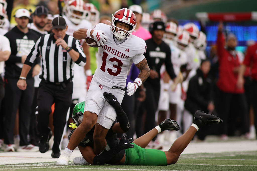 Indiana wide receiver Elijah Sarratt (13) attempts to break a tackle by Oregon defensive back Brandon Finney, bottom, during the second half of an NCAA college football game, Saturday, Oct. 11, 2025, in Eugene, Ore. (AP Photo/Lydia Ely)