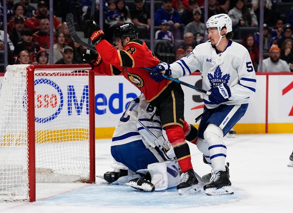 Ottawa Senators' Tim Stutzle, top left, skates into Toronto Maple Leafs goaltender Joseph Woll, bottom left, as Maple Leafs' Philippe Myers, right, defends, during second-period NHL hockey game action in Ottawa, Ontario, Saturday, March 21, 2026. (Justin Tang/The Canadian Press via AP)