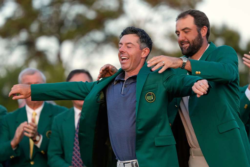 FILE - Scottie Scheffler puts the green Jacket on winner, Rory McIlroy, of Northern Ireland, at the Masters golf tournament, April 13, 2025, in Augusta, Ga. (AP Photo/Ashley Landis, File)