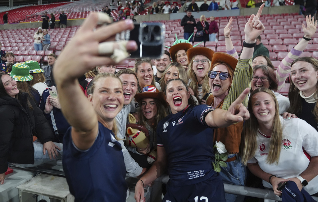 United States' Lotte Sharp, front left, and Ilona Maher, center, pose for a photo with fans after the Women's Rugby World Cup Pool A match in Sunderland, England, Friday, Aug. 22, 2025. (Mike Egerton/PA via AP)