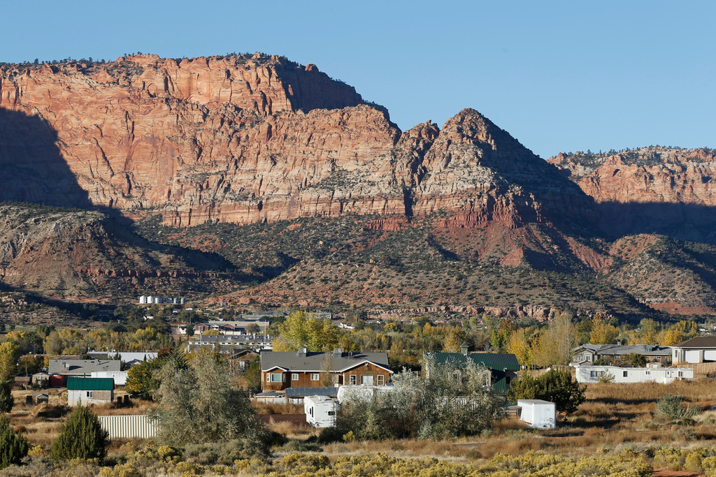 FILE - Hildale, Utah, sitting at the base of Red Rock Cliff mountains, with its sister city, Colorado City, Ariz., in the foreground, on Oct. 26, 2017. (AP Photo/Rick Bowmer, File)