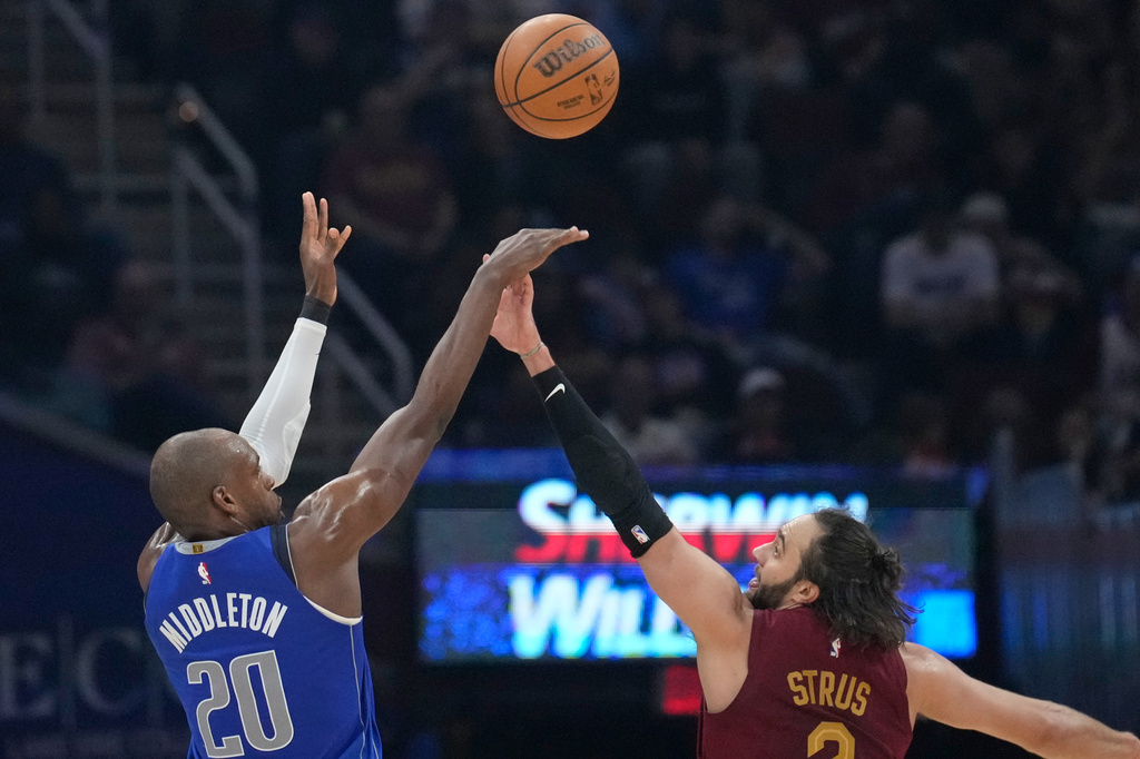 Dallas Mavericks forward Khris Middleton (20) shoots over Cleveland Cavaliers guard Max Strus in the first half of an NBA basketball game in Cleveland, Sunday, March 15, 2026. (AP Photo/Sue Ogrocki)