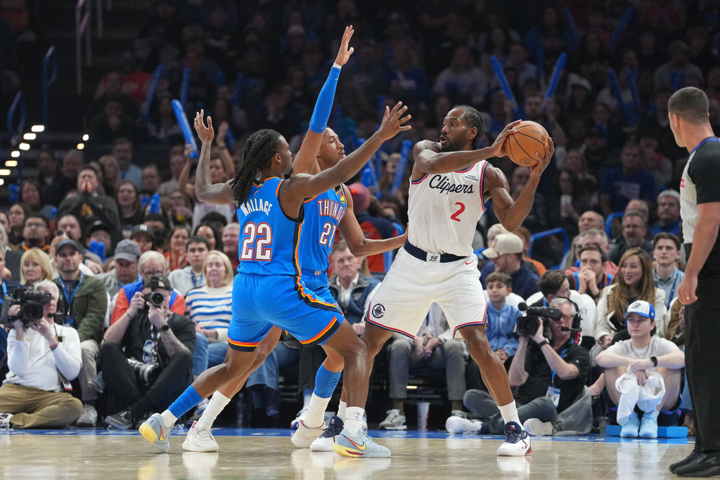 Oklahoma City Thunder guards Cason Wallace (22) and Aaron Wiggins (21) defend against Los Angeles Clippers forward Kawhi Leonard (2) during the first half of an NBA basketball game, Thursday, Dec. 18, 2025, in Oklahoma City. (AP Photo/Kyle Phillips)