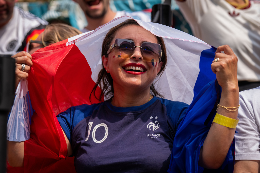 A French fan shields themselves from the sun during the World Cup semifinal soccer match between Spain and France at a watch party at the Rockefeller Center fan village, Tuesday, July 14, 2026, in New York. (AP Photo/Adam Gray)