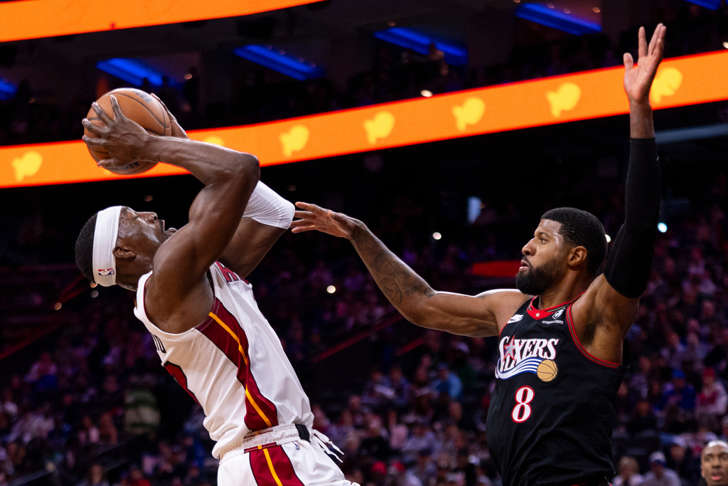 Miami Heat's Bam Adebayo, left, looks to shoot against Philadelphia 76ers' Paul George, right, during the first half of an NBA basketball game, Sunday, Nov. 23, 2025, in Philadelphia. (AP Photo/Chris Szagola)