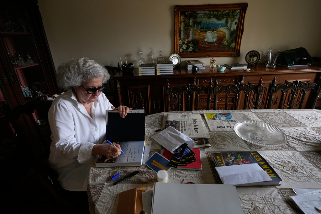 Anissa Helou, 74, one of the Middle East's most acclaimed cooks and food writers, signs a copy of her new book at her late mother's apartment in the Mount Lebanon town of Ballouneh, Thursday, July 2, 2026. (AP Photo/Hussein Malla)