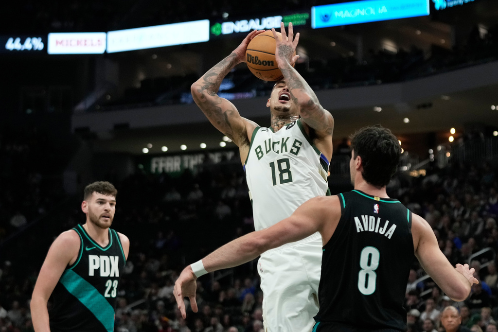 Milwaukee Bucks' Kyle Kuzma (18) drives to the basket between Portland Trail Blazers' Deni Avdija (8) and Donovan Clingan during the first half of an NBA basketball game, Monday, Nov. 24, 2025, in Milwaukee. (AP Photo/Aaron Gash)