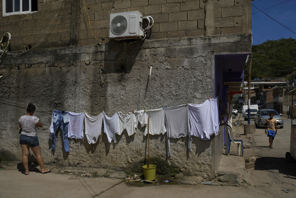 A woman hangs clothes to dry in the fishing community of El Morro de Puerto Santo, on Venezuela's Paria Peninsula, Sunday, Sept. 14, 2025. (AP Photo/Ariana Cubillos)
