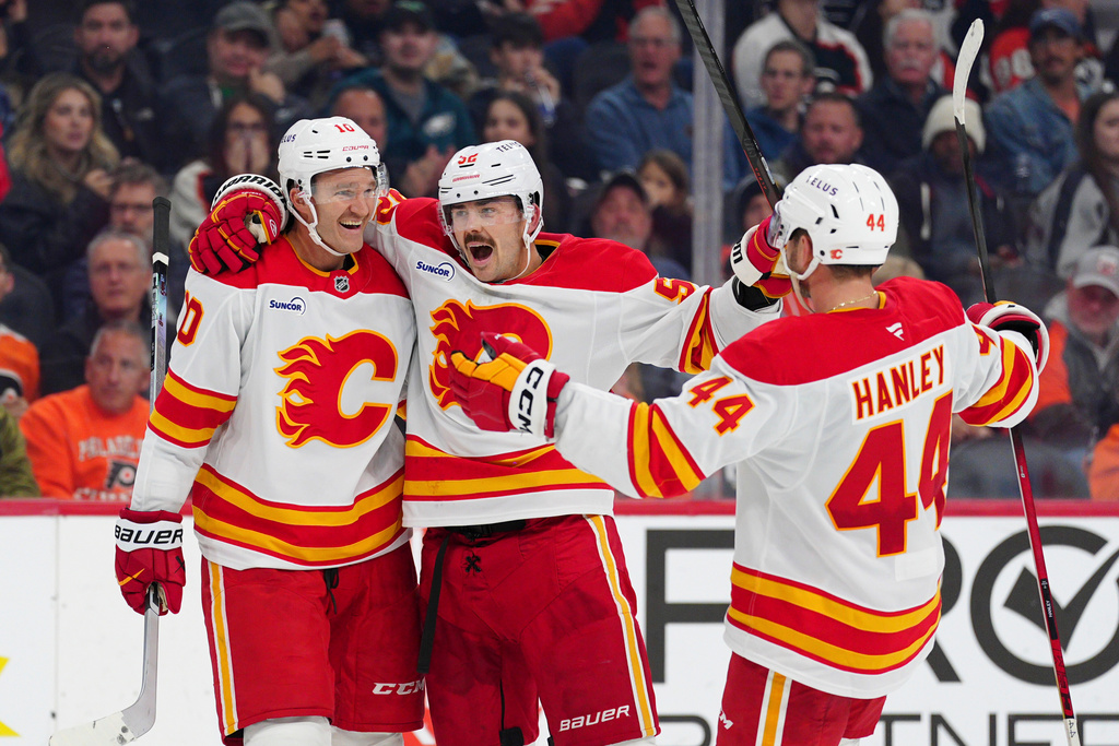Calgary Flames' Jonathan Huberdeau, left, celebrates after his goal with Mackenzie Weegar (52) and Joel Hanley (44) during the third period of an NHL hockey game against the Philadelphia Flyers, Sunday, Nov. 2, 2025, in Philadelphia. (AP Photo/Derik Hamilton)