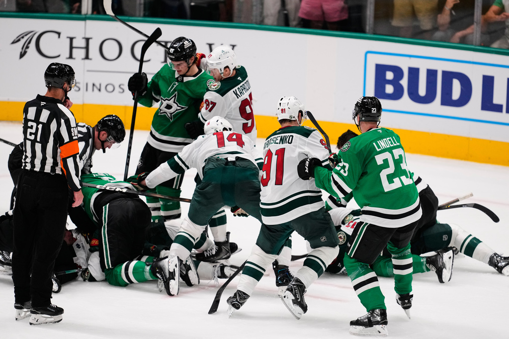 Referee TJ Luxmore (21) looks on as fights break out between the Dallas Stars and Minnesota Wild in the third period of an NHL hockey game Thursday, April 9, 2026, in Arlington, Texas. (AP Photo/Tony Gutierrez)