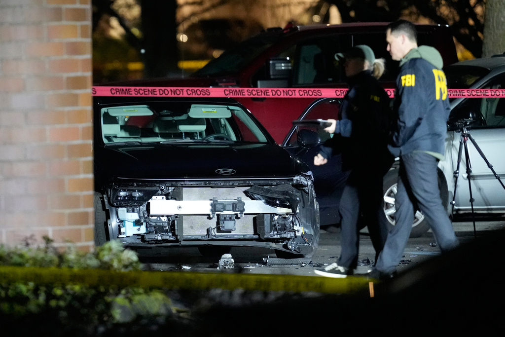 A damaged car is seen as law enforcement officials work the scene following reports that federal immigration officers shot and wounded people in Portland, Ore., Thursday, Jan. 8, 2026. (AP Photo/Jenny Kane)