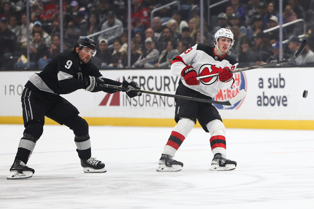 New Jersey Devils defenseman Luke Hughes, right, passes the puck against Los Angeles Kings right wing Adrian Kempe (9) during the first period of an NHL hockey game, Saturday, Nov. 1, 2025, in Los Angeles. (AP Photo/Jessie Alcheh)