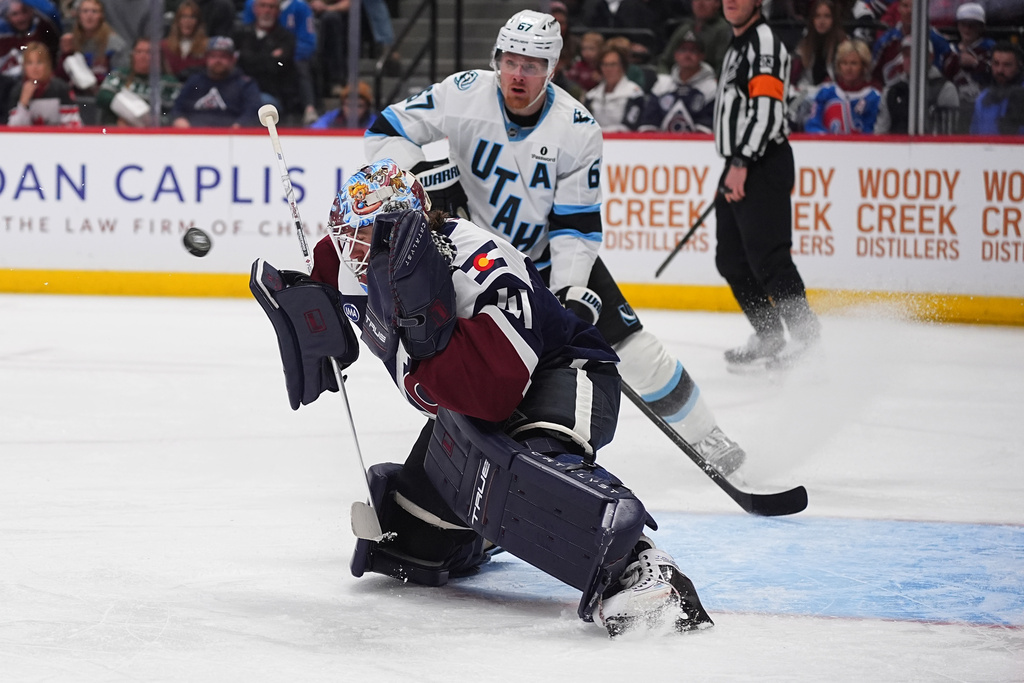 Colorado Avalanche goaltender Scott Wedgewood, front, deflects a shot as Utah Mammoth left wing Lawson Crouse looks on in the second period of an NHL hockey game Tuesday, Dec. 23, 2025, in Denver. (AP Photo/David Zalubowski)
