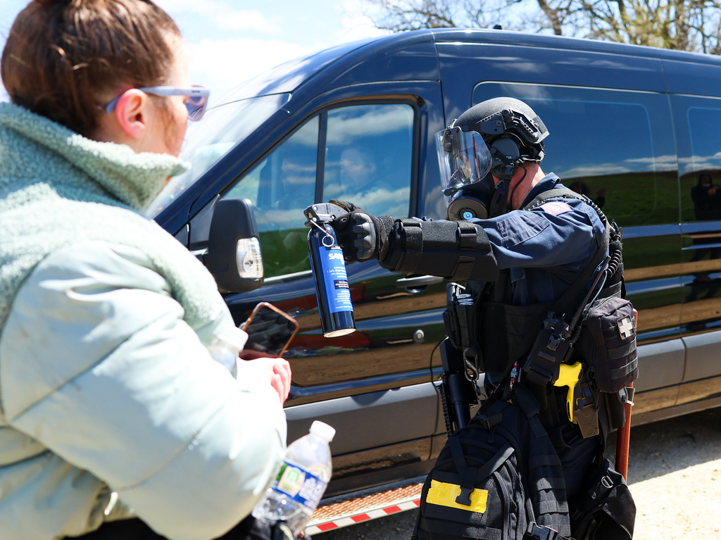 A Wisconsin State Patrol officer points a can of mace at activists as officers make way for a van to leave the grounds of Ridglan Farms beagle breeding and research facility on Saturday, April 18, 2026 in Blue Mounds, Wis. (Owen Ziliak/Wisconsin State Journal via AP)