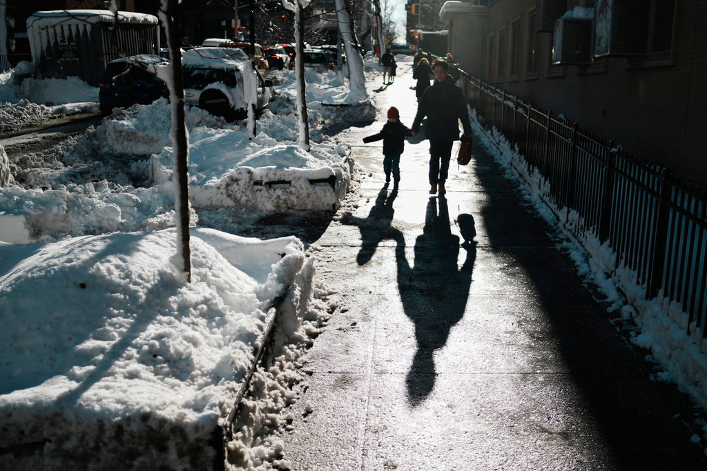 A man walks a boy to school, Tuesday, Feb. 24, 2026, in New York. (AP Photo/Eduardo Munoz Alvarez)