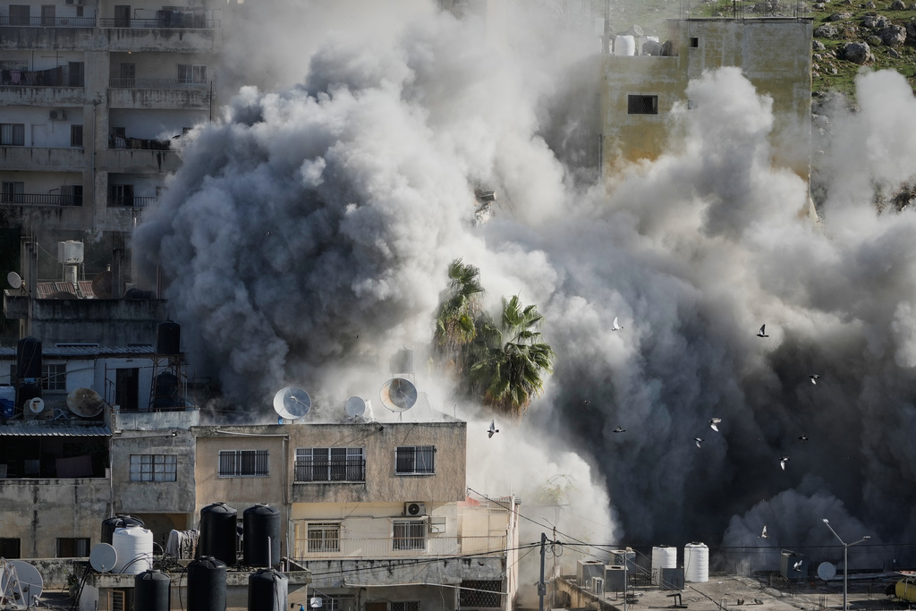 Smoke rises as Israeli forces demolish the home of Abdul Karim Sanoubar, a suspected Palestinian militant who has been accused by Israel of planting bombs on buses in central Israel, in Nablus, West Bank, Tuesday, Dec. 2, 2025. (AP Photo/Majdi Mohammed)