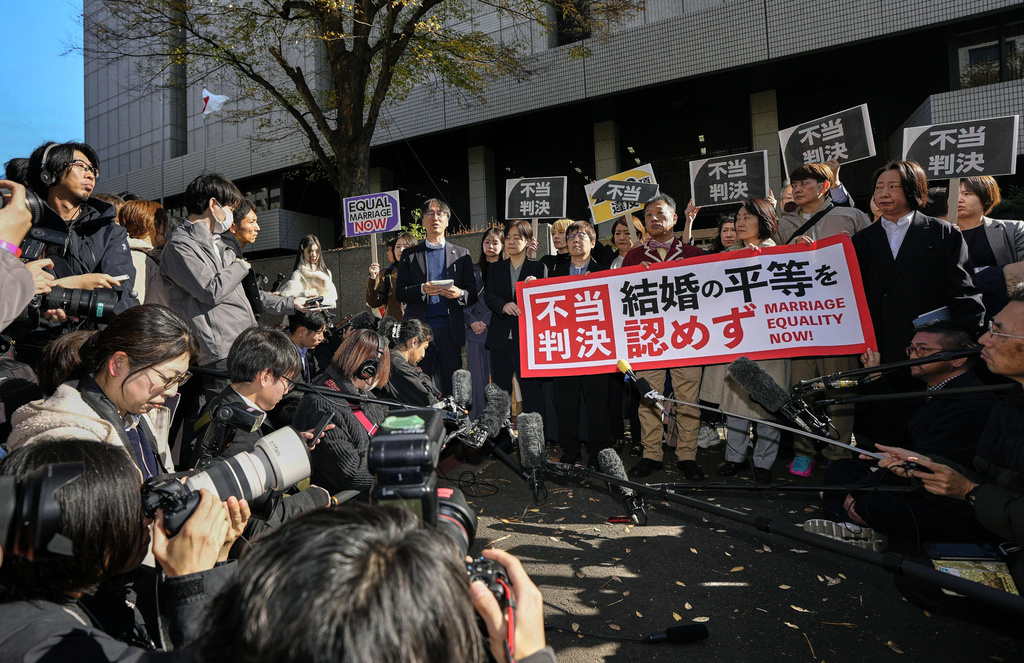 Plaintiffs of same-sex couples, their lawyers and supporters hold placards reading, "Unjust ruling," stand outside a high court after its ruling on same-sex marriage in Tokyo, Friday, Nov. 28, 2025. (Miki Matsuzaki/Kyodo News via AP)