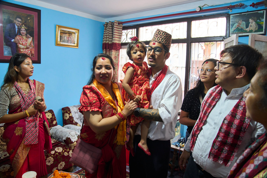Nepal's newly appointed living goddess, Kumari Aryatara Shakya, is carried by her father and mother as they pose for photographs at their personal residence in Kathmandu, Nepal, Tuesday, Sept. 30, 2025. (AP Photo/Niranjan Shrestha)