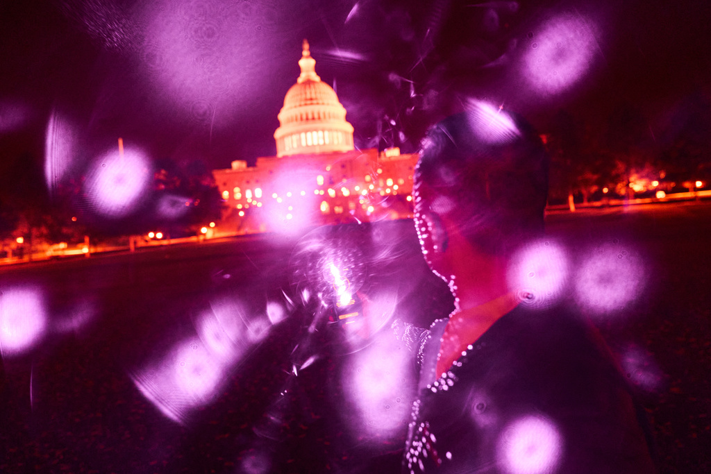 Infrared facial recognition beams are emitted from a cellphone held by a Uyghur man, who asked to remain anonymous for safety reasons, as he’s photographed in front of the U.S. Capitol, Oct. 16, 2025, in Washington, where he’s living in exile after escaping China. (AP Photo/David Goldman)