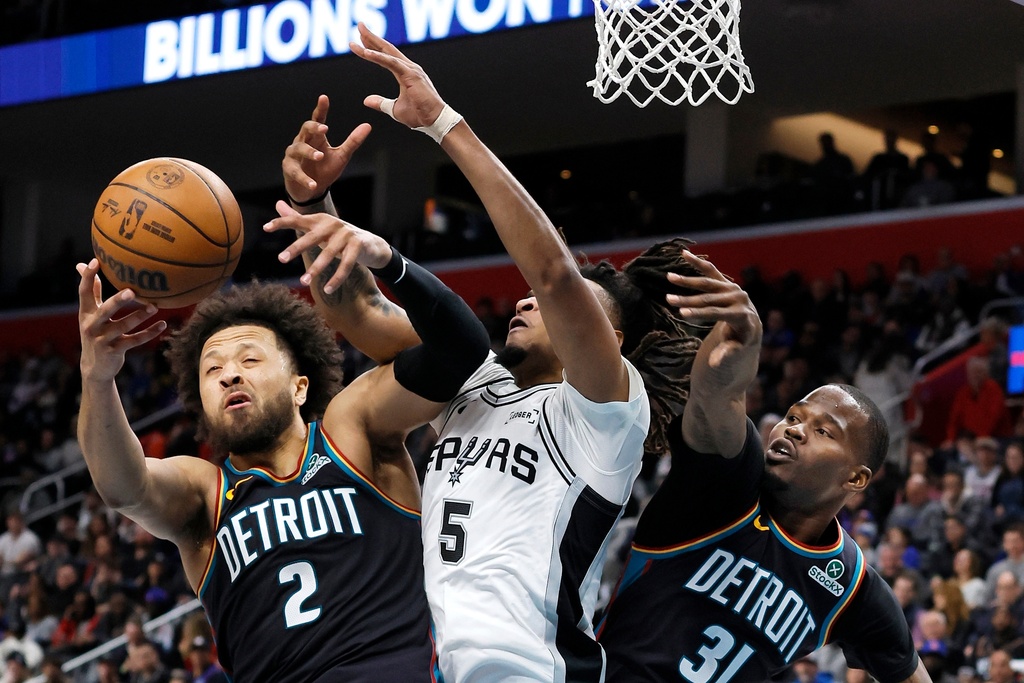 Detroit Pistons guard Cade Cunningham (2) battles San Antonio Spurs guard Stephon Castle (5) for a rebound with Pistons guard Javonte Green (31) helping on the play during the first half of an NBA basketball game Monday, Feb. 23, 2026, in Detroit. (AP Photo/Duane Burleson)